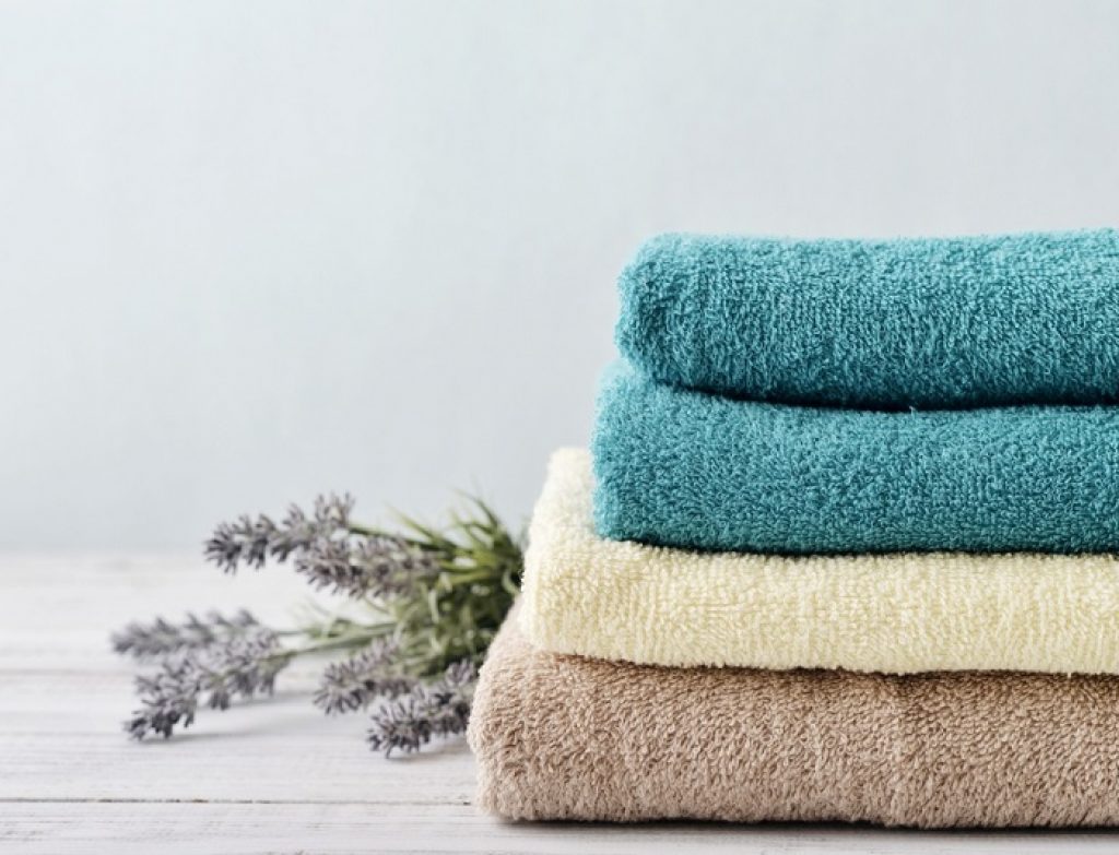 Stack,Of,Bath,Towels,With,Lavender,Flowers,On,Light,Wooden